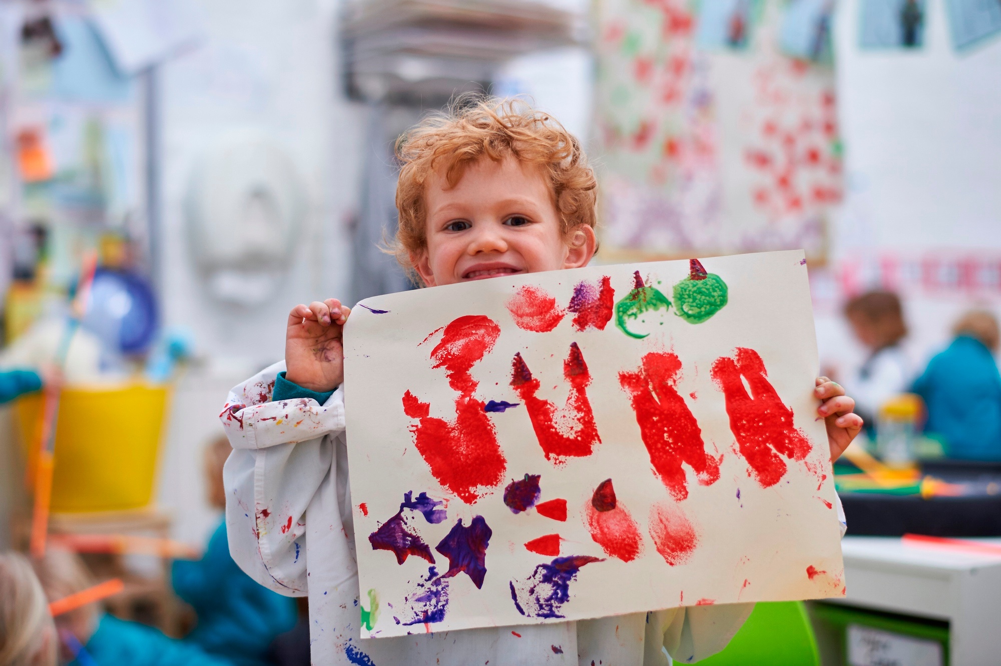 Image of pupil holding up painting to illustrate link to 'Childcare Vouchers' page