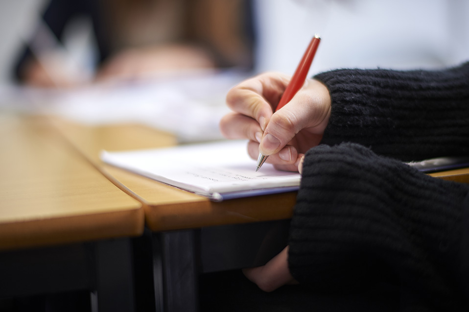 Image of student writing to illustrate link to 'Financial Assistance' page