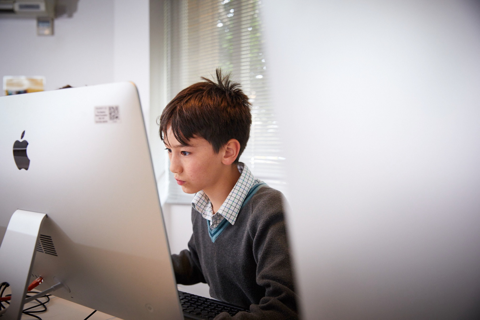 Image of student at computer to illustrate link to 'FAQs' page