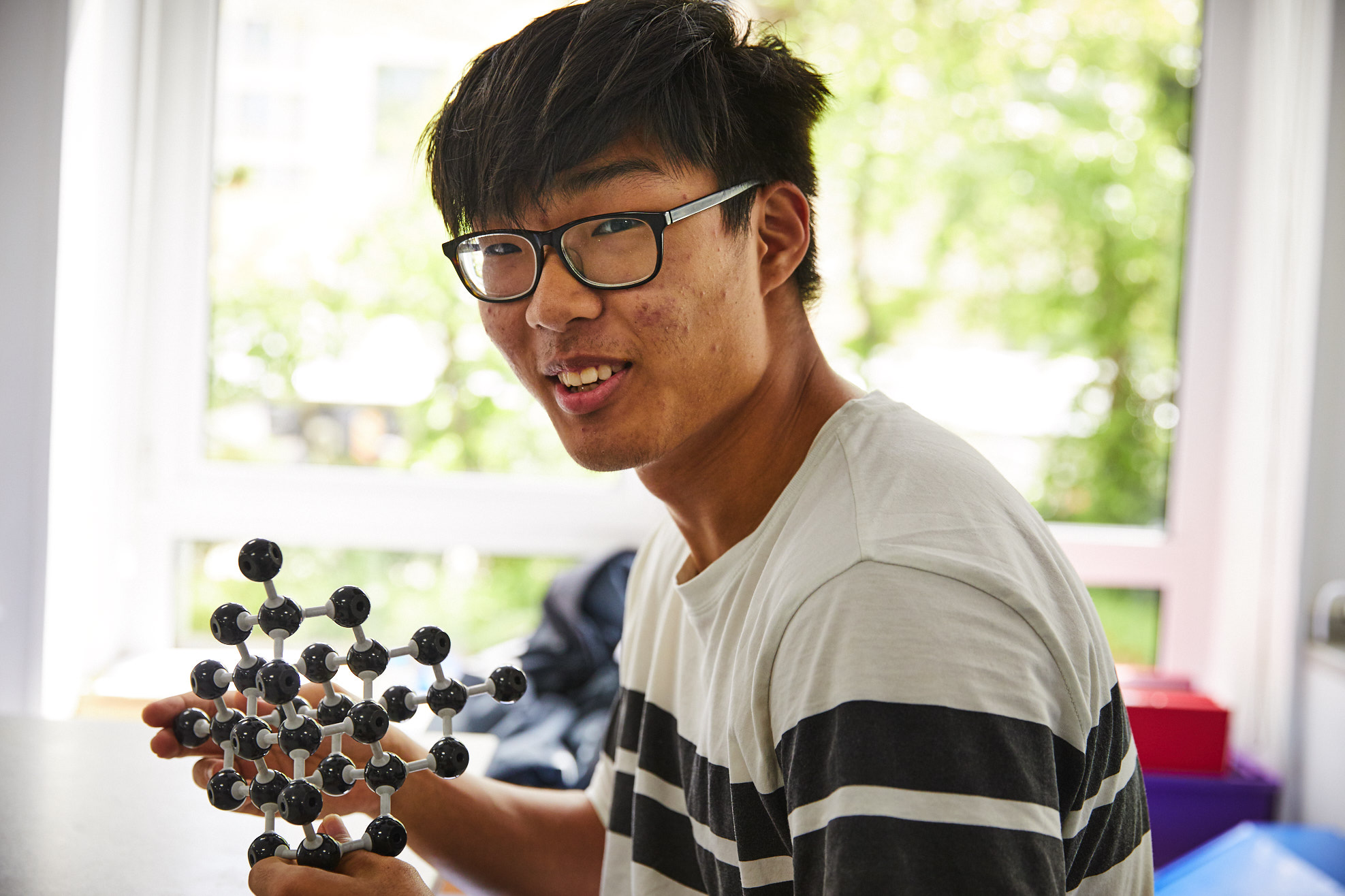 Sixth form student holding ball and stick model