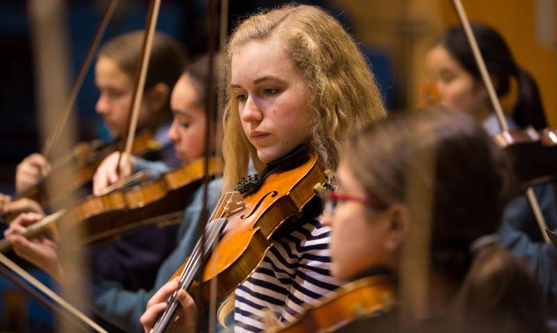 Student playing a violin in school ochestra 