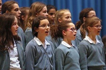 Image of students in choir singing to illustrate link to 'Music' page