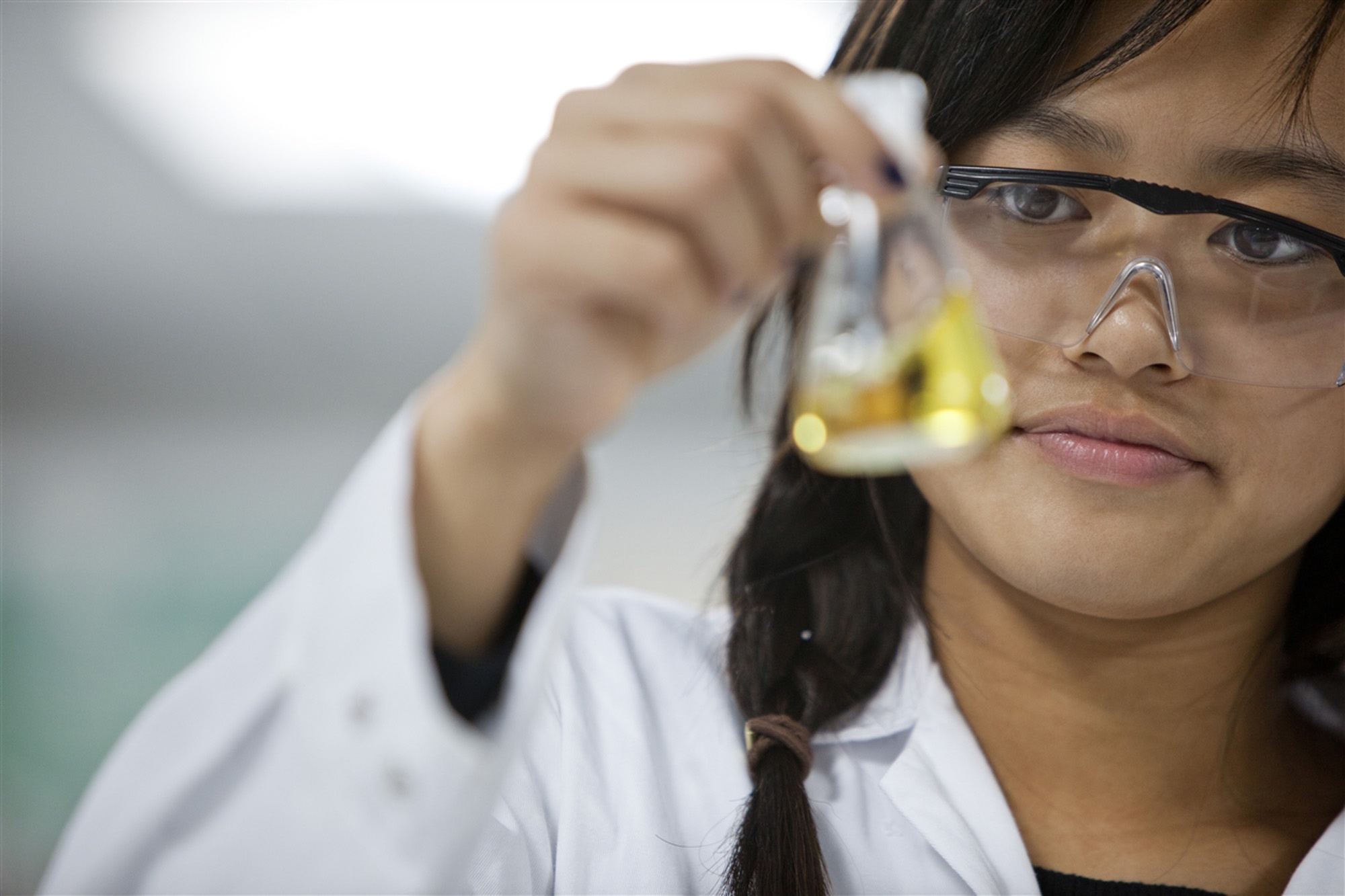 Image of student looking at flask in science class to illustrate link to 'Chemistry' page