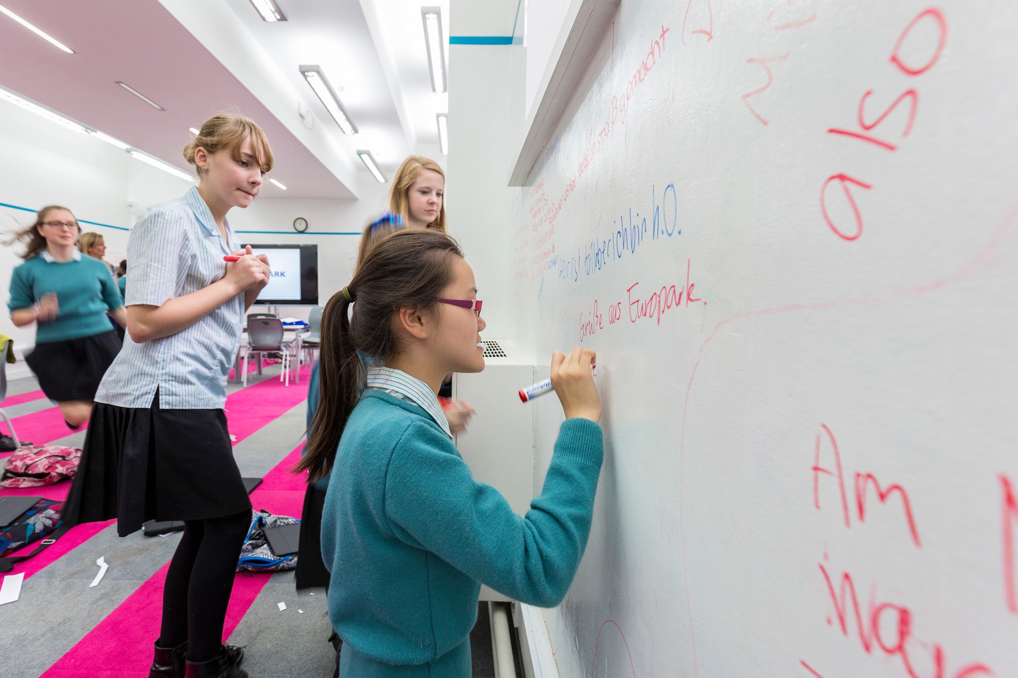 Image of students writing on whiteboard to illustrate link to 'Geography' page